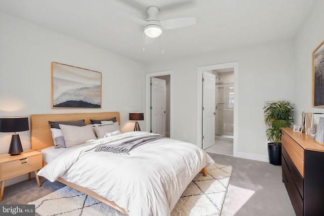 bedroom with ensuite bathroom, light colored carpet, and ceiling fan