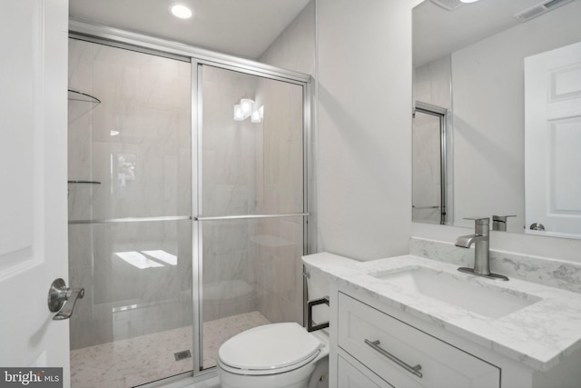 bathroom with a shower with door, vanity, and toilet