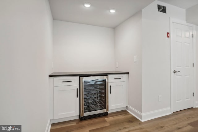 bar featuring wine cooler, white cabinetry, and light hardwood / wood-style floors