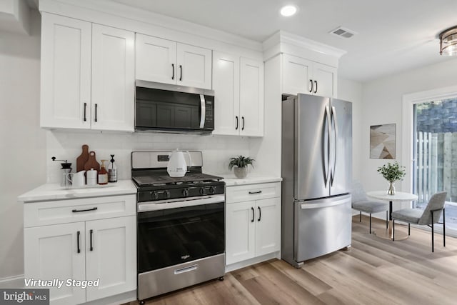 kitchen featuring white cabinetry, decorative backsplash, stainless steel appliances, and light hardwood / wood-style floors