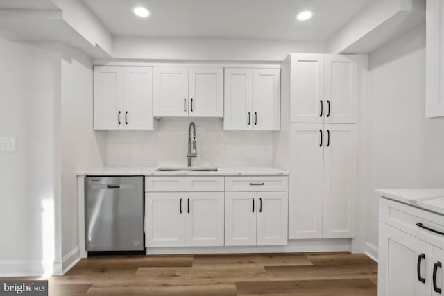 kitchen featuring white cabinetry, backsplash, sink, hardwood / wood-style floors, and stainless steel dishwasher