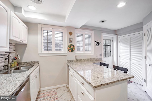 kitchen with white cabinetry, light stone countertops, sink, stainless steel dishwasher, and backsplash