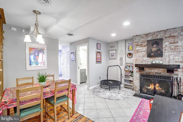 tiled dining space with a fireplace and a chandelier