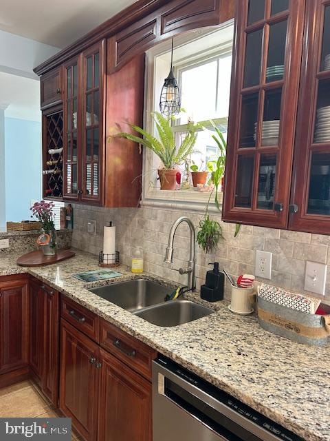 kitchen featuring light stone counters, decorative backsplash, sink, and stainless steel dishwasher