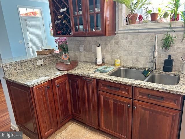 kitchen featuring decorative backsplash, light stone counters, sink, and light tile patterned floors