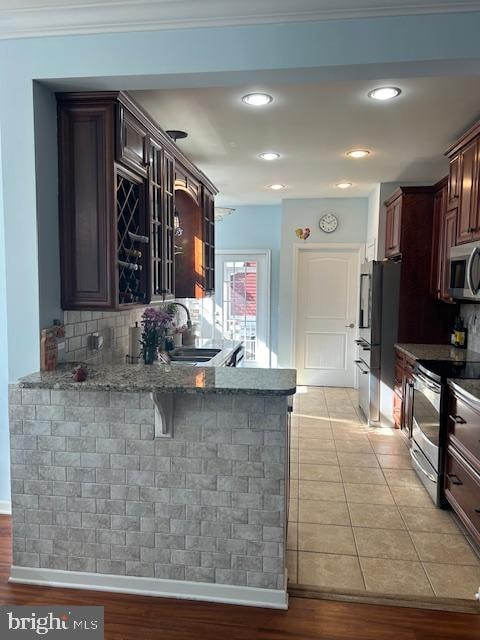 kitchen featuring kitchen peninsula, decorative backsplash, light hardwood / wood-style flooring, ornamental molding, and stainless steel appliances