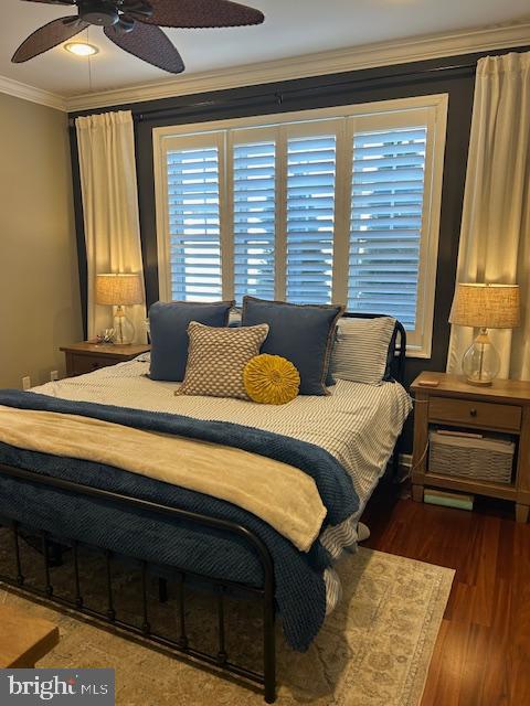 bedroom featuring ceiling fan, ornamental molding, and dark hardwood / wood-style floors