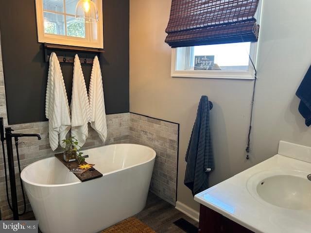 bathroom featuring tile walls, vanity, a bathtub, and hardwood / wood-style flooring