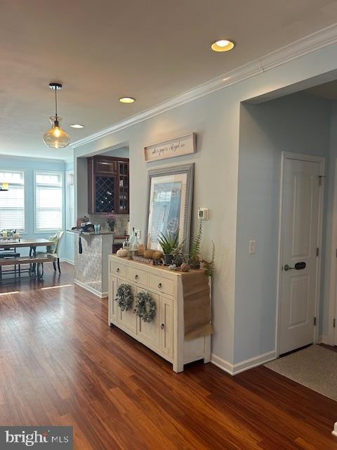 interior space with white cabinetry, ornamental molding, dark hardwood / wood-style flooring, and pendant lighting