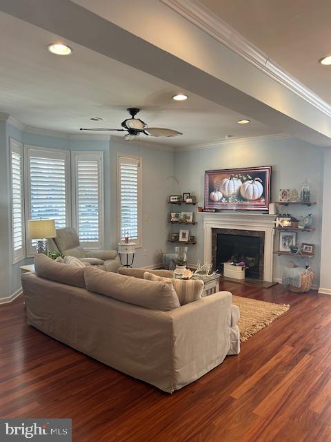 living room featuring dark wood-type flooring, crown molding, and ceiling fan