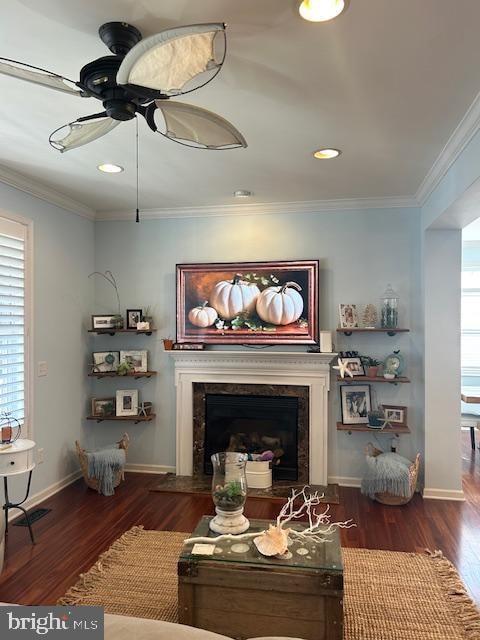 living room featuring dark wood-type flooring, crown molding, a high end fireplace, and ceiling fan