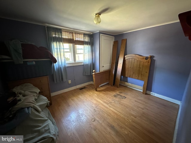 bedroom with crown molding and hardwood / wood-style floors