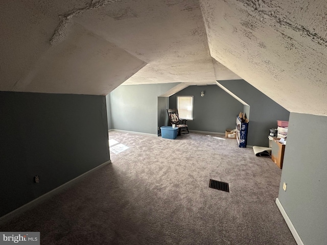 bonus room with carpet, vaulted ceiling, and a textured ceiling