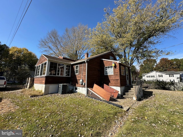 view of side of property featuring central air condition unit, a yard, and a sunroom