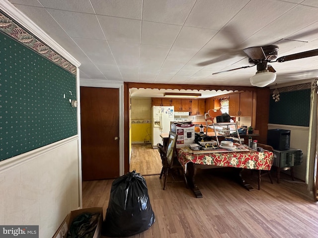 bedroom featuring crown molding, ceiling fan, white fridge with ice dispenser, and light wood-type flooring