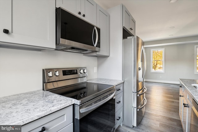 kitchen featuring light stone counters, appliances with stainless steel finishes, dark hardwood / wood-style flooring, and gray cabinets