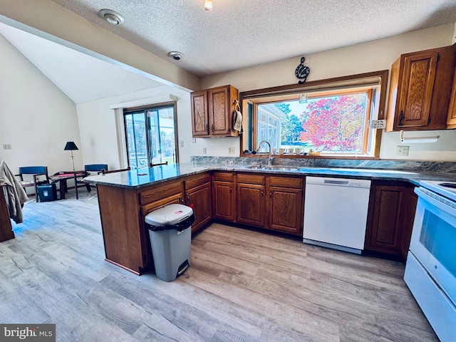 kitchen featuring kitchen peninsula, a textured ceiling, light wood-type flooring, sink, and white appliances