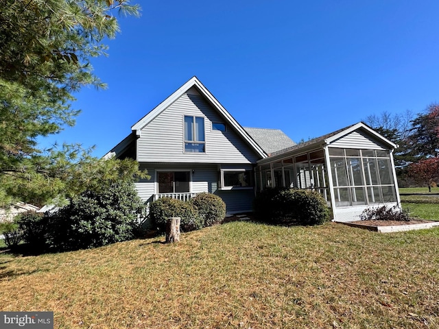 rear view of property featuring a sunroom and a lawn