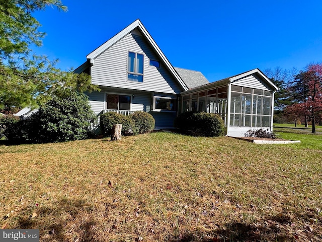 rear view of property featuring a yard and a sunroom