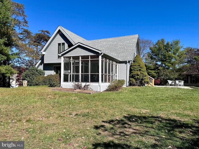 rear view of house with a yard and a sunroom