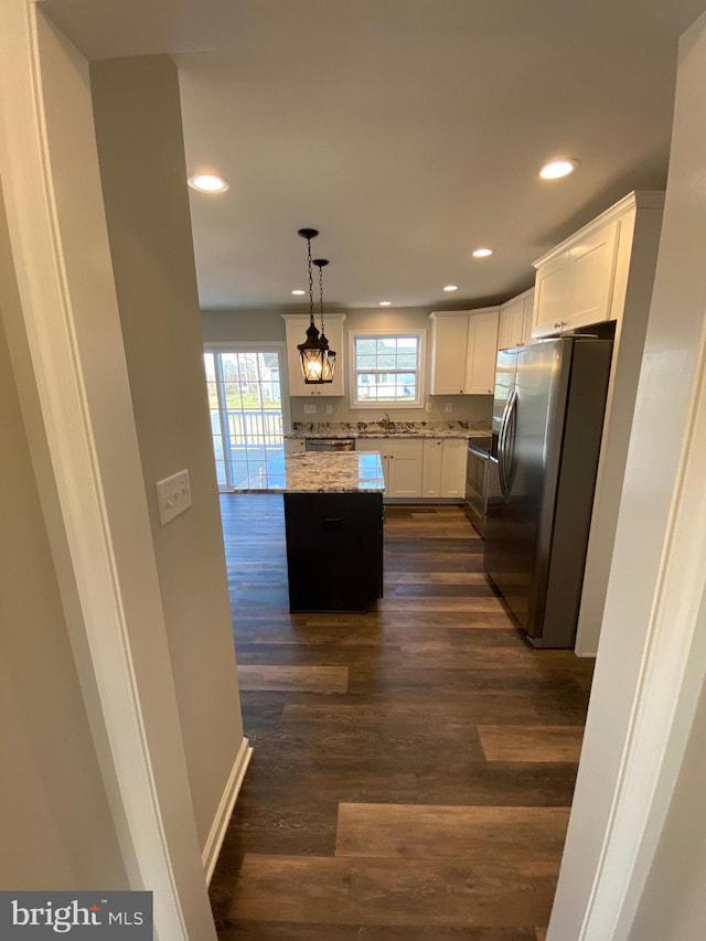 kitchen featuring a kitchen island, dark wood-type flooring, stainless steel fridge with ice dispenser, decorative light fixtures, and white cabinetry