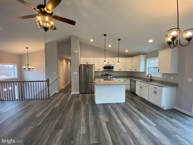 kitchen featuring lofted ceiling, hanging light fixtures, white cabinets, appliances with stainless steel finishes, and dark hardwood / wood-style flooring