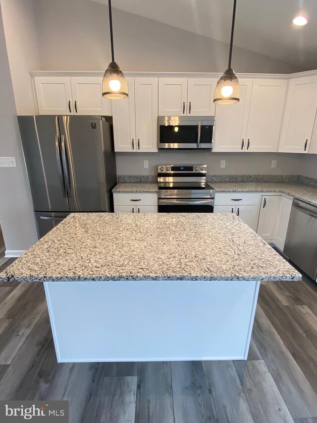 kitchen with vaulted ceiling, appliances with stainless steel finishes, pendant lighting, and white cabinets