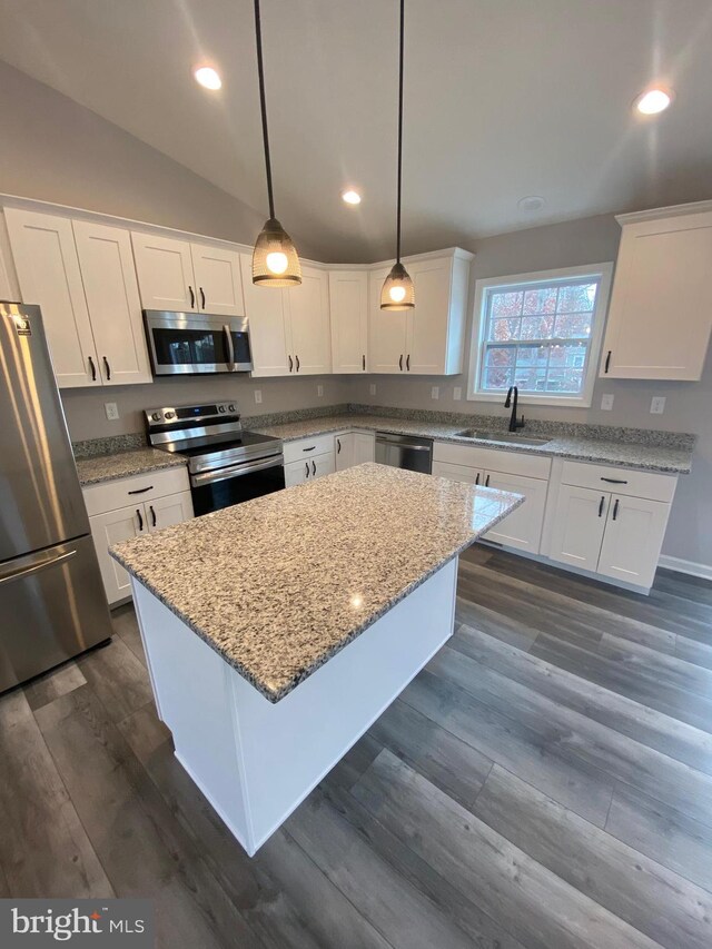 kitchen with lofted ceiling, hanging light fixtures, sink, white cabinets, and appliances with stainless steel finishes