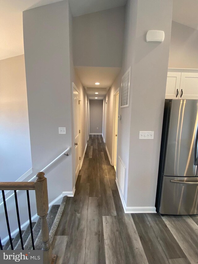 hallway with high vaulted ceiling and dark hardwood / wood-style flooring