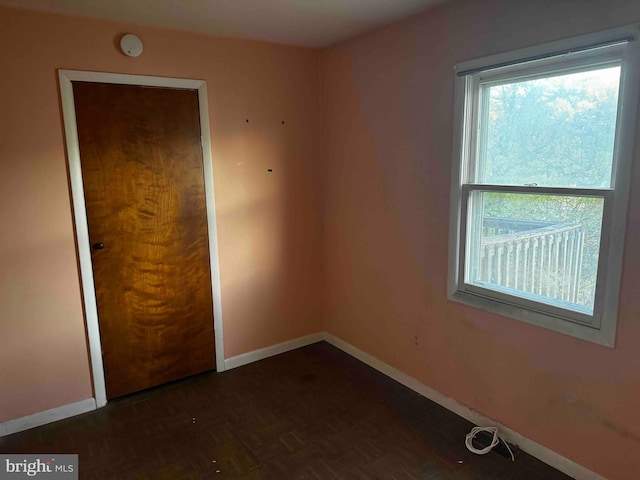 unfurnished bedroom featuring a closet and dark parquet flooring