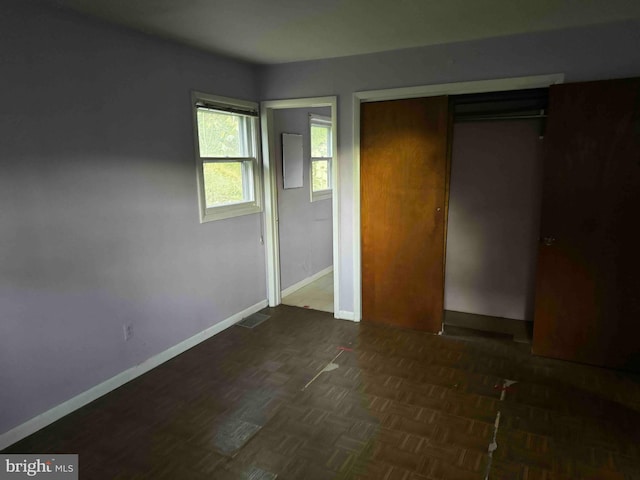 unfurnished bedroom with a closet and dark parquet flooring