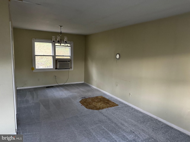 spare room featuring a notable chandelier, cooling unit, and dark colored carpet