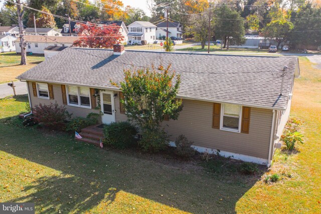 single story home with a chimney, roof with shingles, and a front lawn
