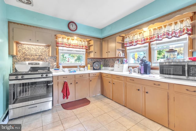 kitchen with stainless steel appliances, decorative backsplash, light tile patterned floors, and plenty of natural light