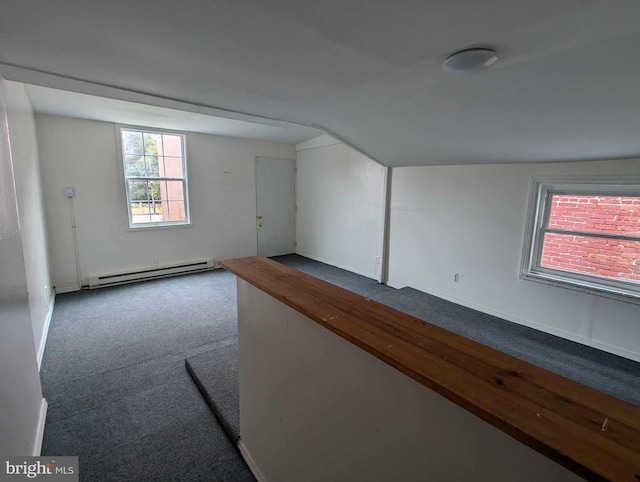 carpeted empty room featuring lofted ceiling and baseboard heating