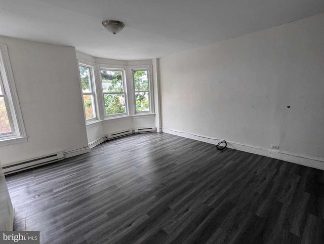 empty room with dark hardwood / wood-style floors, baseboard heating, and plenty of natural light