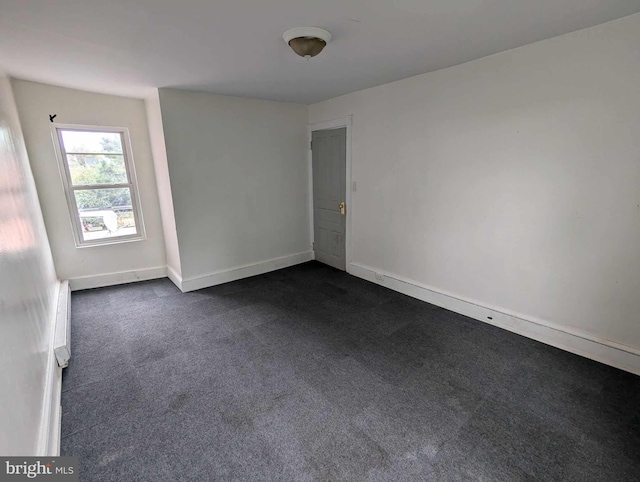 spare room featuring dark carpet