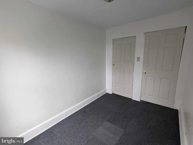 unfurnished bedroom with dark carpet