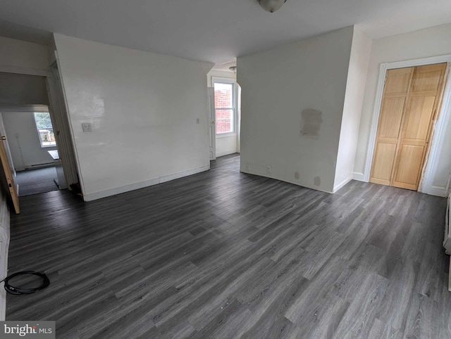 unfurnished room featuring dark wood-type flooring, a baseboard radiator, and plenty of natural light