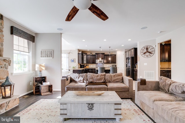 living room featuring ceiling fan and dark hardwood / wood-style flooring