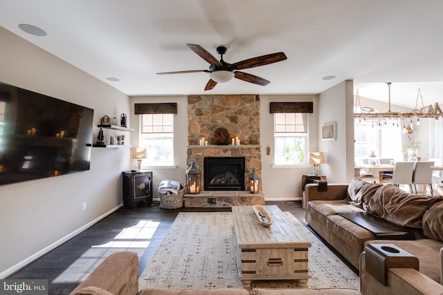 living room with hardwood / wood-style flooring, ceiling fan, and a stone fireplace