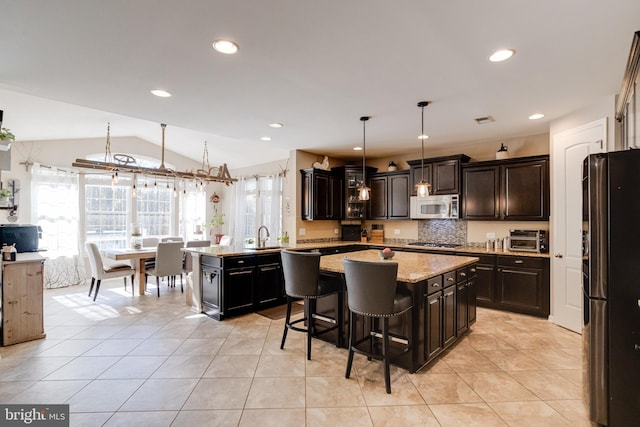 kitchen featuring lofted ceiling, hanging light fixtures, light tile patterned floors, a kitchen island, and stainless steel appliances