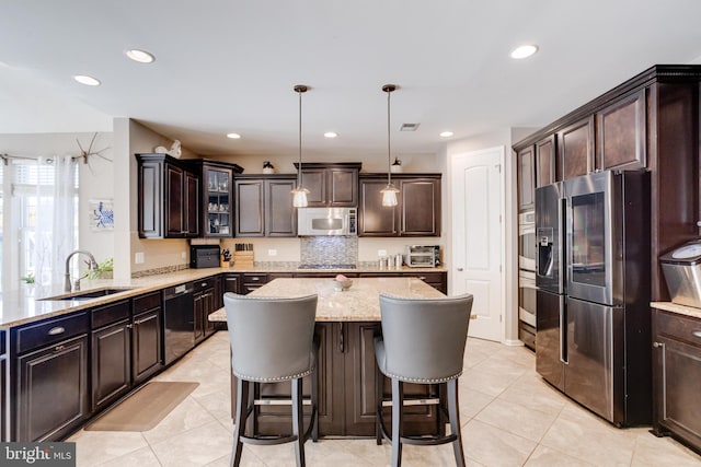 kitchen with dark brown cabinetry, sink, a center island, hanging light fixtures, and stainless steel appliances