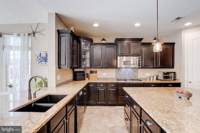 kitchen with stainless steel appliances, sink, pendant lighting, and dark brown cabinetry