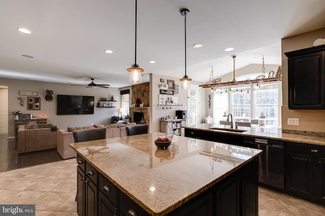 kitchen with light stone countertops, a kitchen island, black dishwasher, and sink