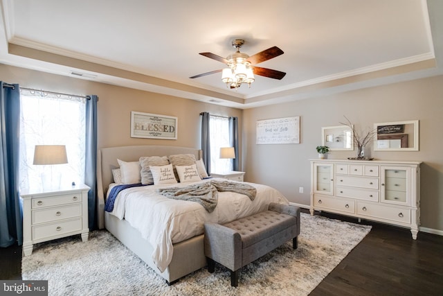 bedroom with crown molding, a tray ceiling, wood-type flooring, and ceiling fan