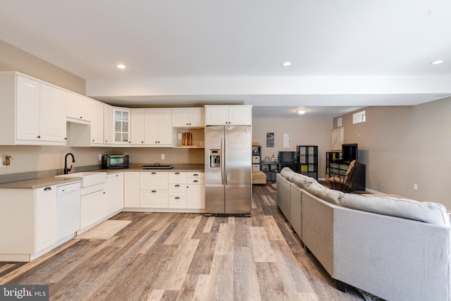 kitchen featuring dishwasher, white cabinetry, sink, stainless steel refrigerator with ice dispenser, and light hardwood / wood-style flooring