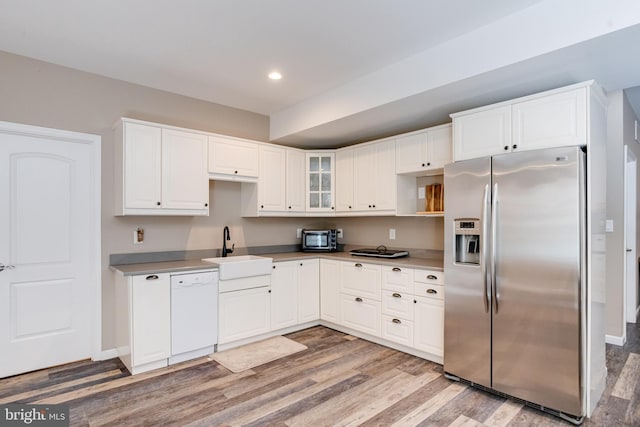 kitchen featuring sink, stainless steel fridge, dishwasher, white cabinetry, and light hardwood / wood-style floors