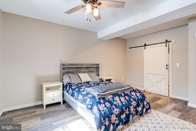 bedroom featuring wood-type flooring, a barn door, and ceiling fan