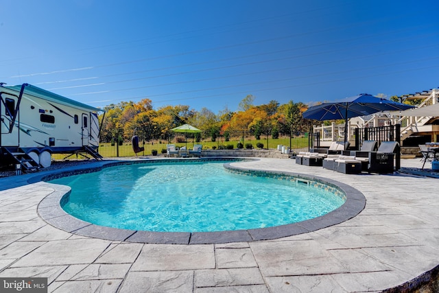 view of pool featuring a patio area and an outdoor living space with a fire pit